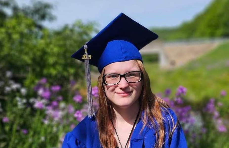 smiling student poses in graduation cap and gown