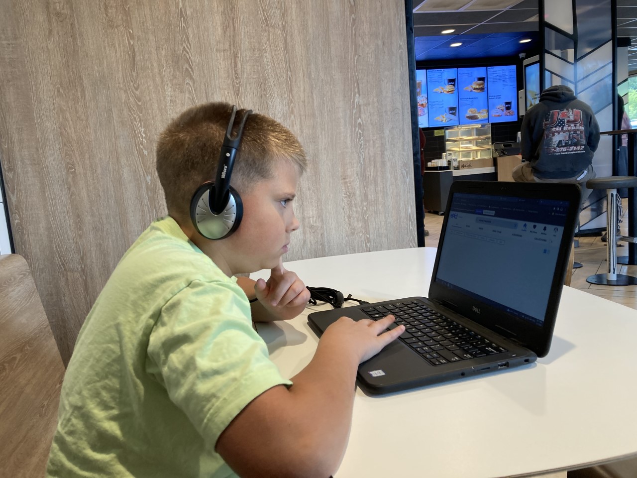 child learning online in a virtual class on a laptop computer with headphones.