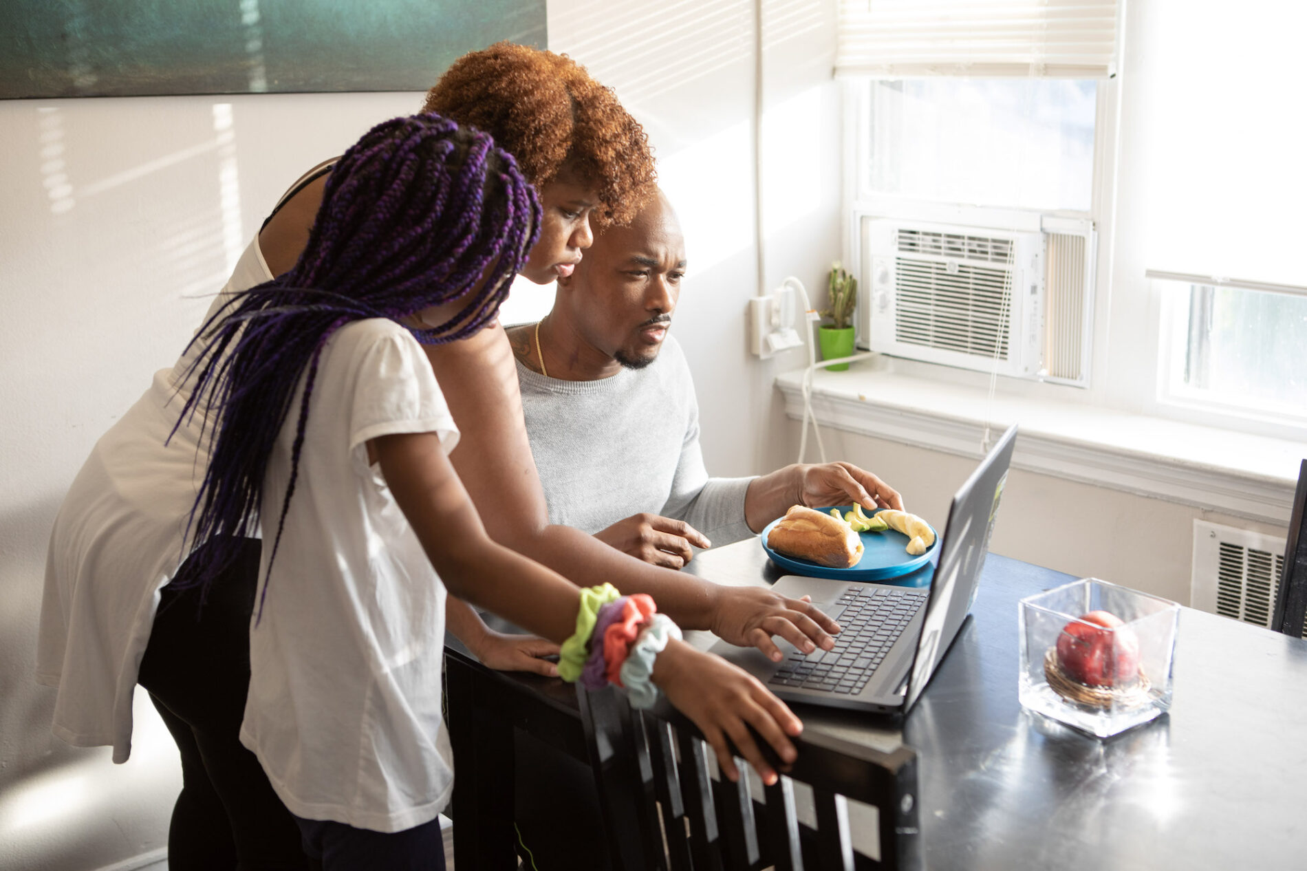Two Insight PA parents and an Insight PA student are looking at a laptop computer together.