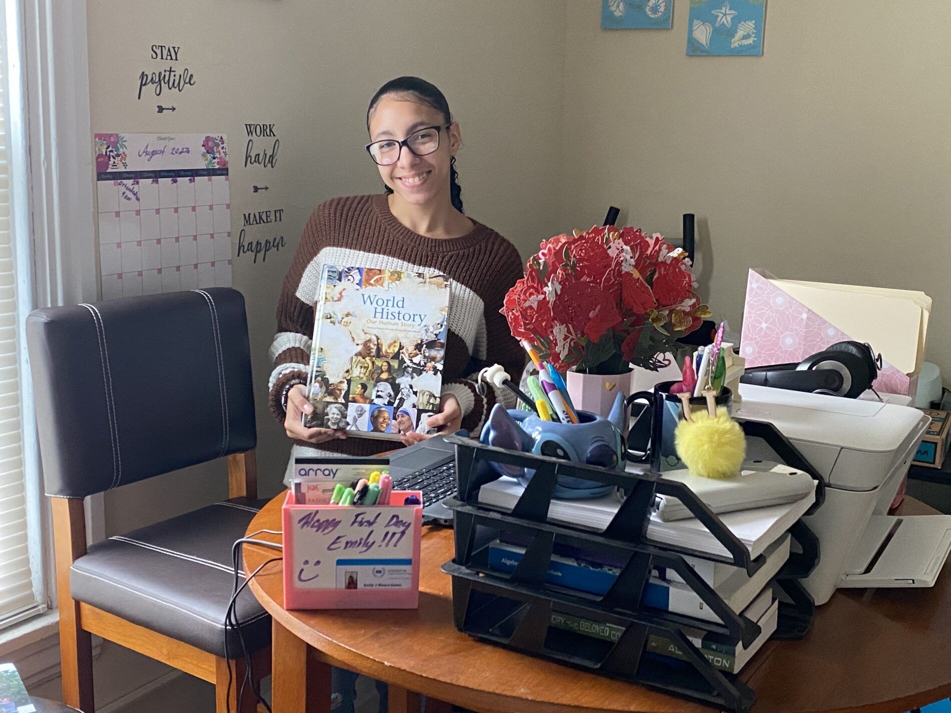 An Insight PA Student smiling at their desk holding a World History book.