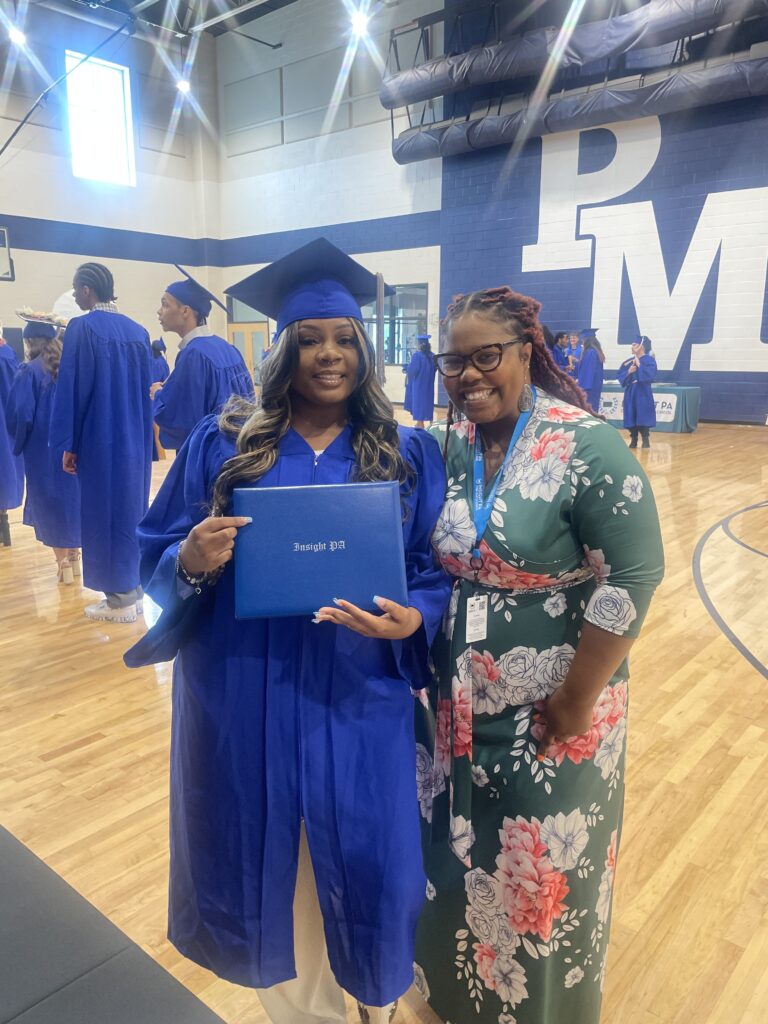 An Insight PA graduate poses with their diploma and an Insight PA staff member at the graduation ceremony.