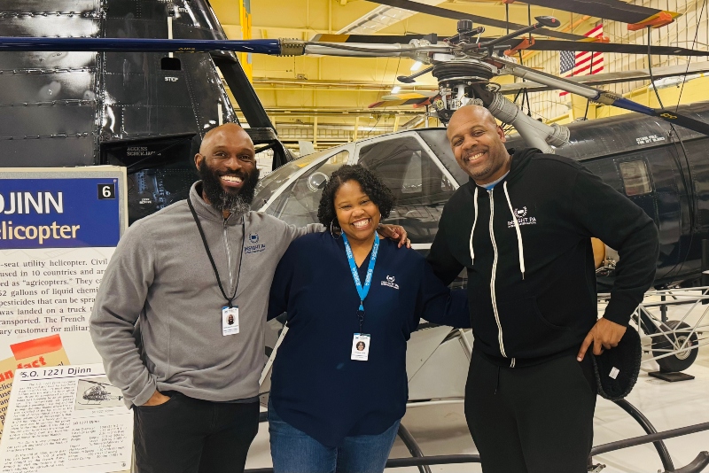 Community Engagement Coordinator Courtland Handy poses with two other Insight PA staff members in front of a Djinn helicopter at the American Helicopter Museum in West Chester, PA.