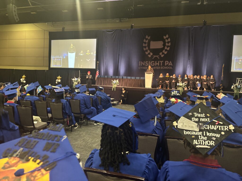 The graduation ceremony at Insight PA. A speaker is at the podium while graduates look on.